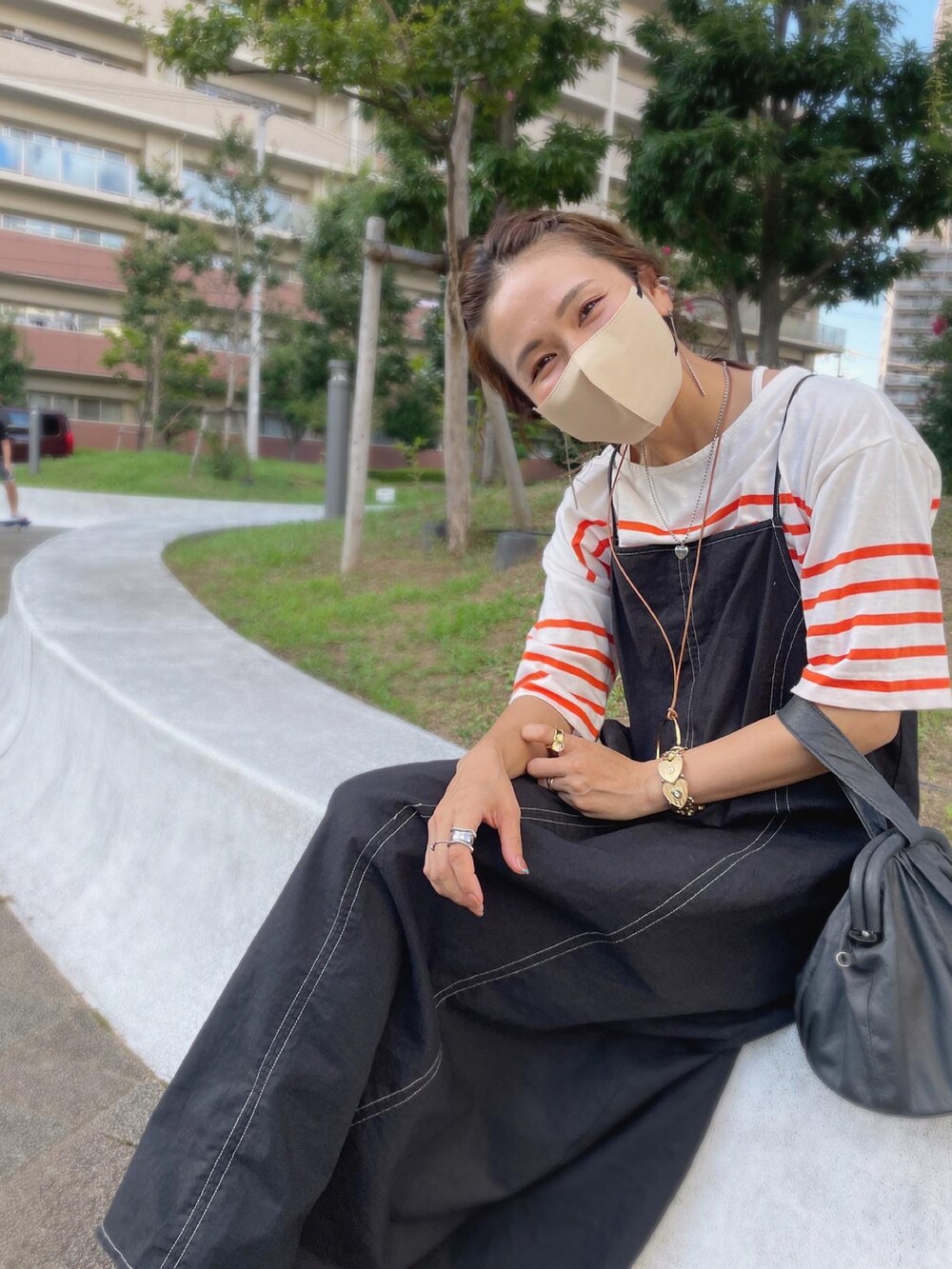 オレンジ系のTシャツ/カットソー、ブラック系のワンピースを着用したレディースの秋コーディネートの4枚目の写真