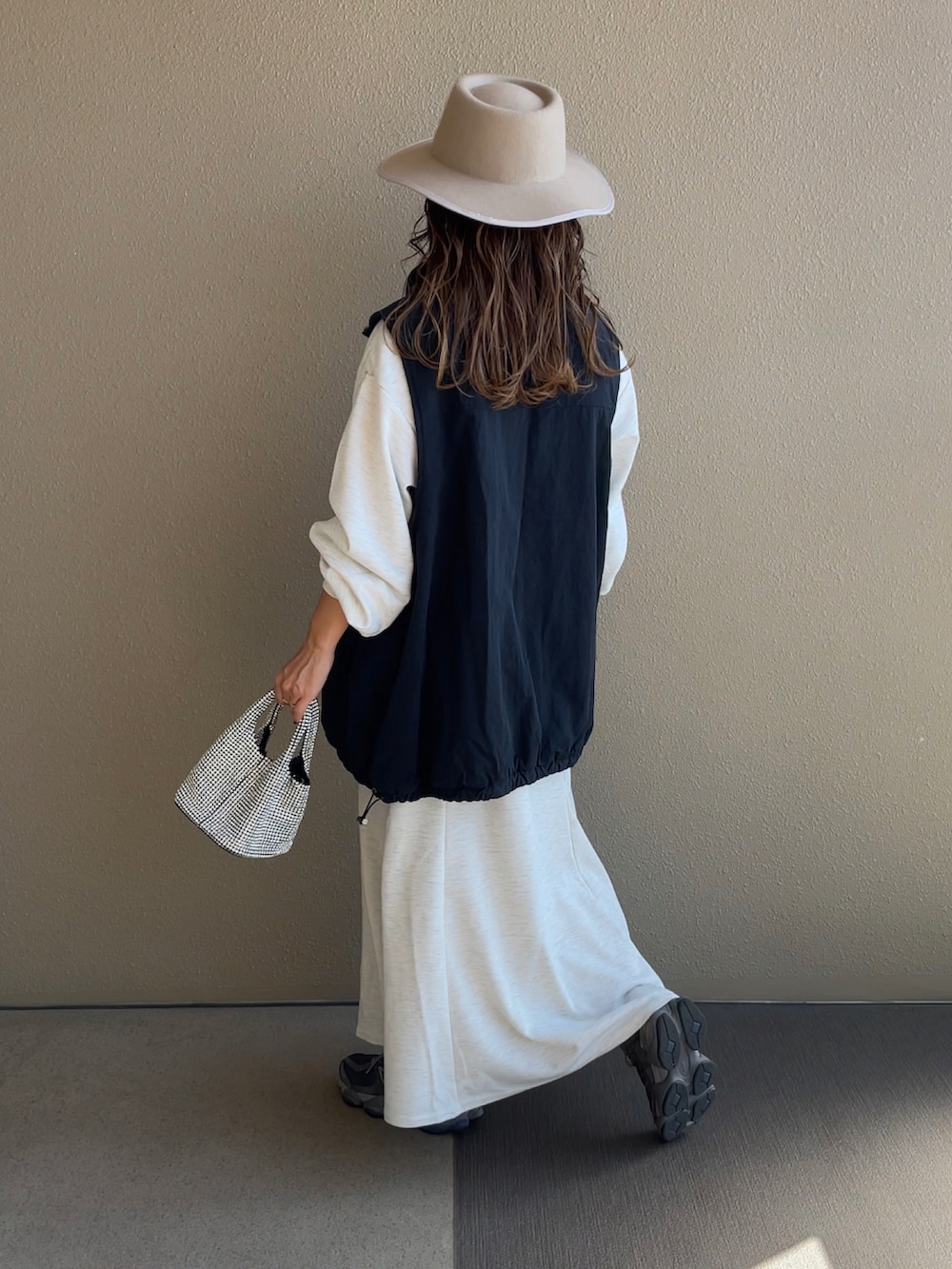 グレー系のワンピース、ブラック系のベストを着用したレディースの秋コーディネートの2枚目の写真