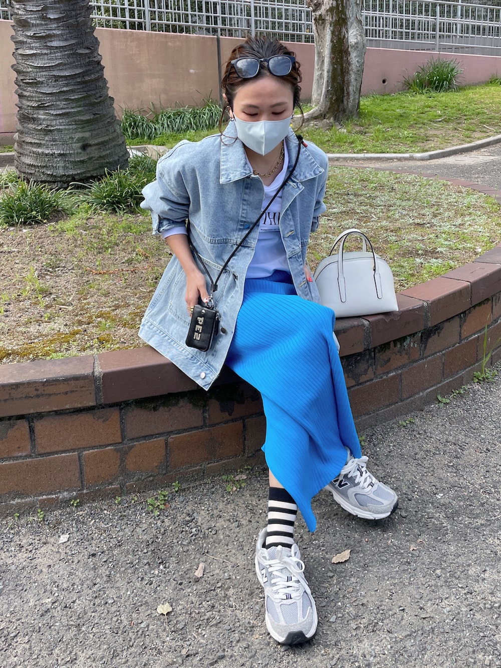 ブルー系のデニムジャケット、ホワイト系のスウェット、ブラック系のカードケースを着用したレディースの春コーディネートの5枚目の写真