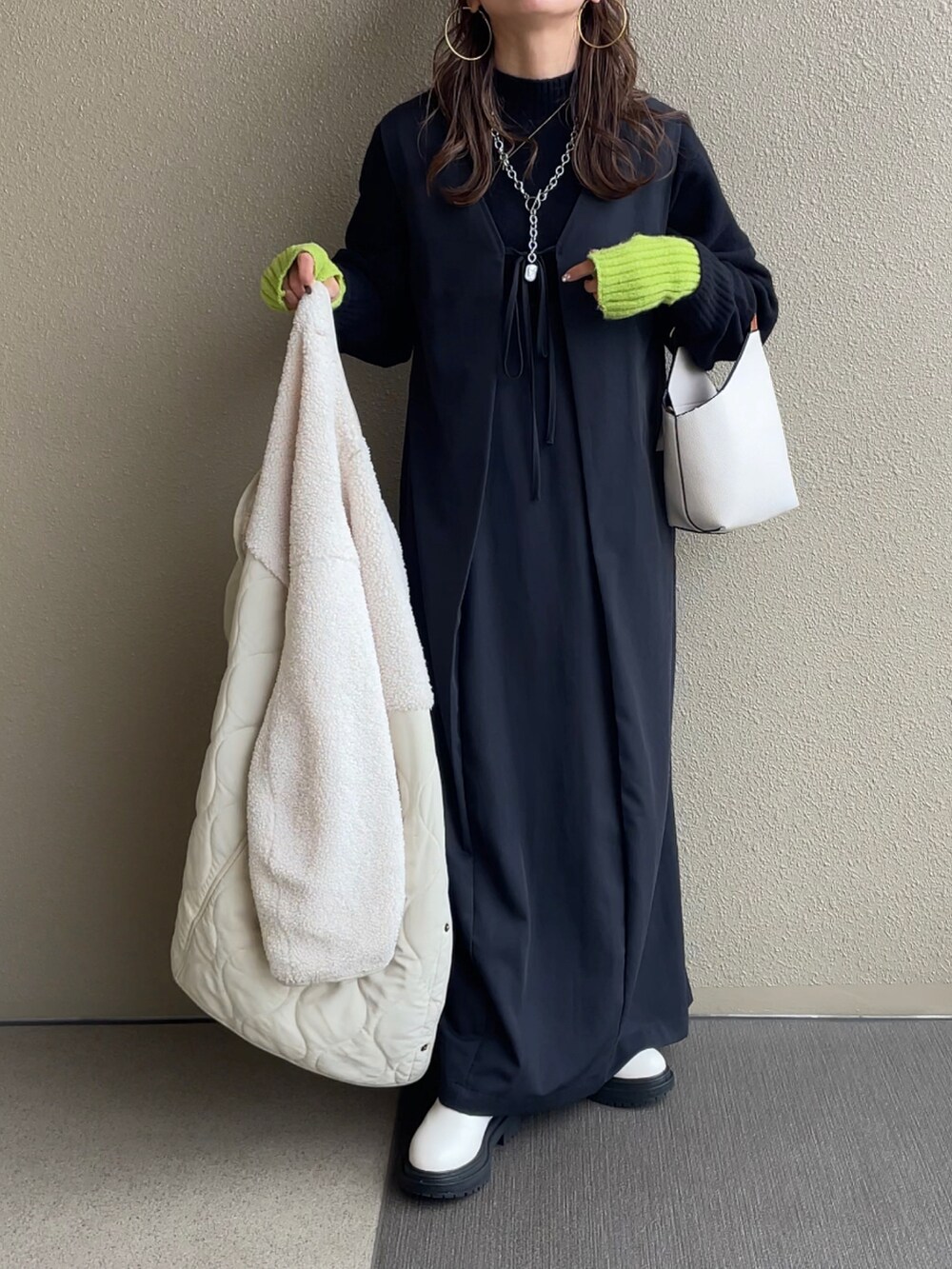 ブラック系のニット/セーター、ホワイト系のスカート、ブラウン系のデニムパンツを着用したレディースの冬コーディネートの3枚目の写真