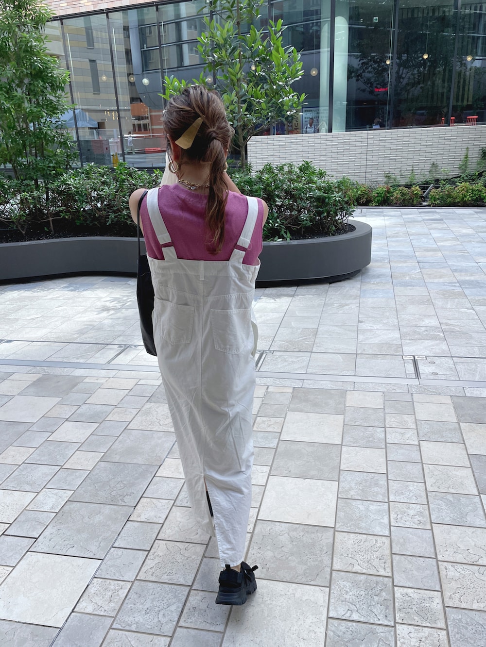 ピンク系のTシャツ/カットソー、ホワイト系のジャンパースカート、ブラック系のショルダーバッグを着用したレディースの夏コーディネートの2枚目の写真