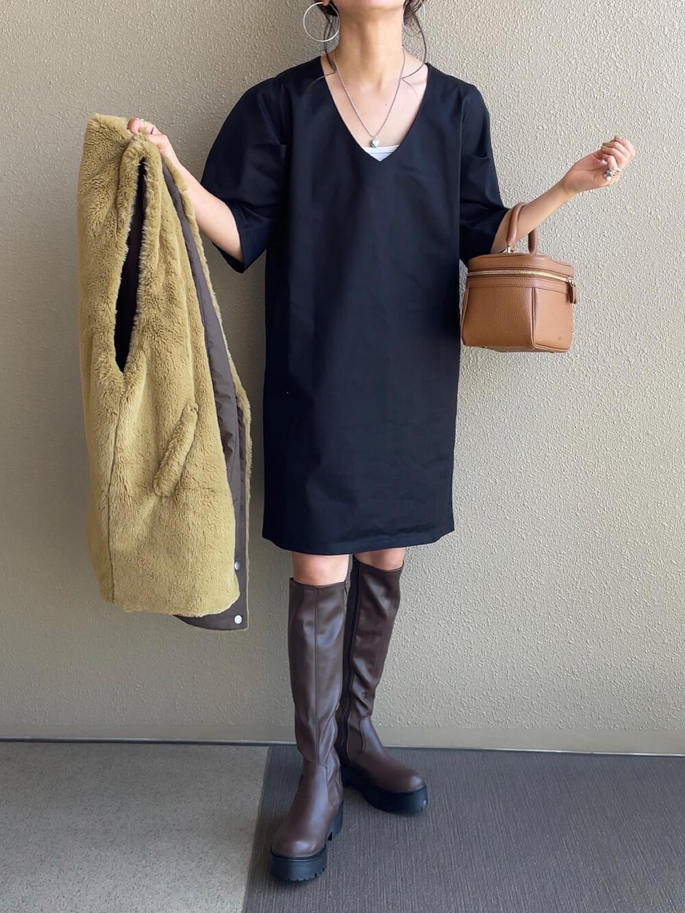 ブラック系のワンピース、イエロー系のベスト、ブラウン系のブーツを着用したレディースの秋コーディネートの2枚目の写真