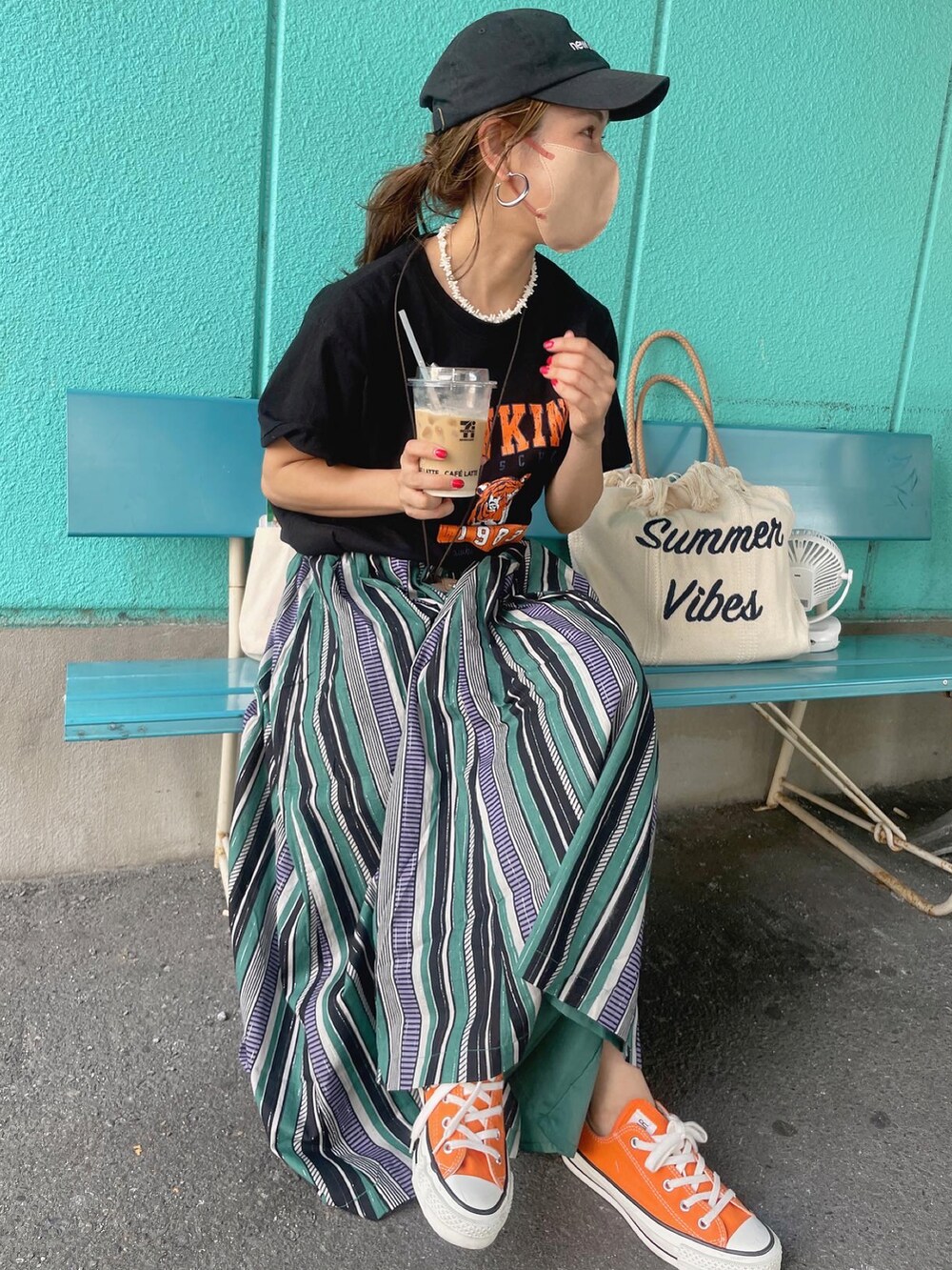グリーン系のスカート、ホワイト系のトートバッグ、オレンジ系のスニーカーを着用したレディースの夏コーディネートの3枚目の写真