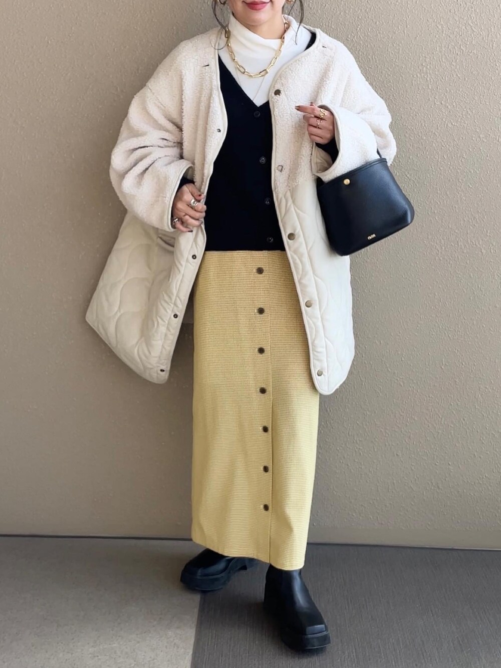 ブラック系のカーディガン/ボレロ、イエロー系のスカート、ホワイト系のノーカラージャケットを着用したレディースの冬コーディネートの5枚目の写真