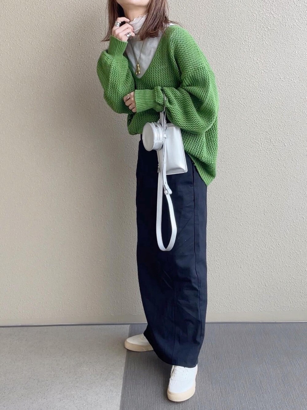 グリーン系のニット/セーター、ブラック系のスカート、ホワイト系のTシャツ/カットソーを着用したレディースの冬コーディネートの3枚目の写真