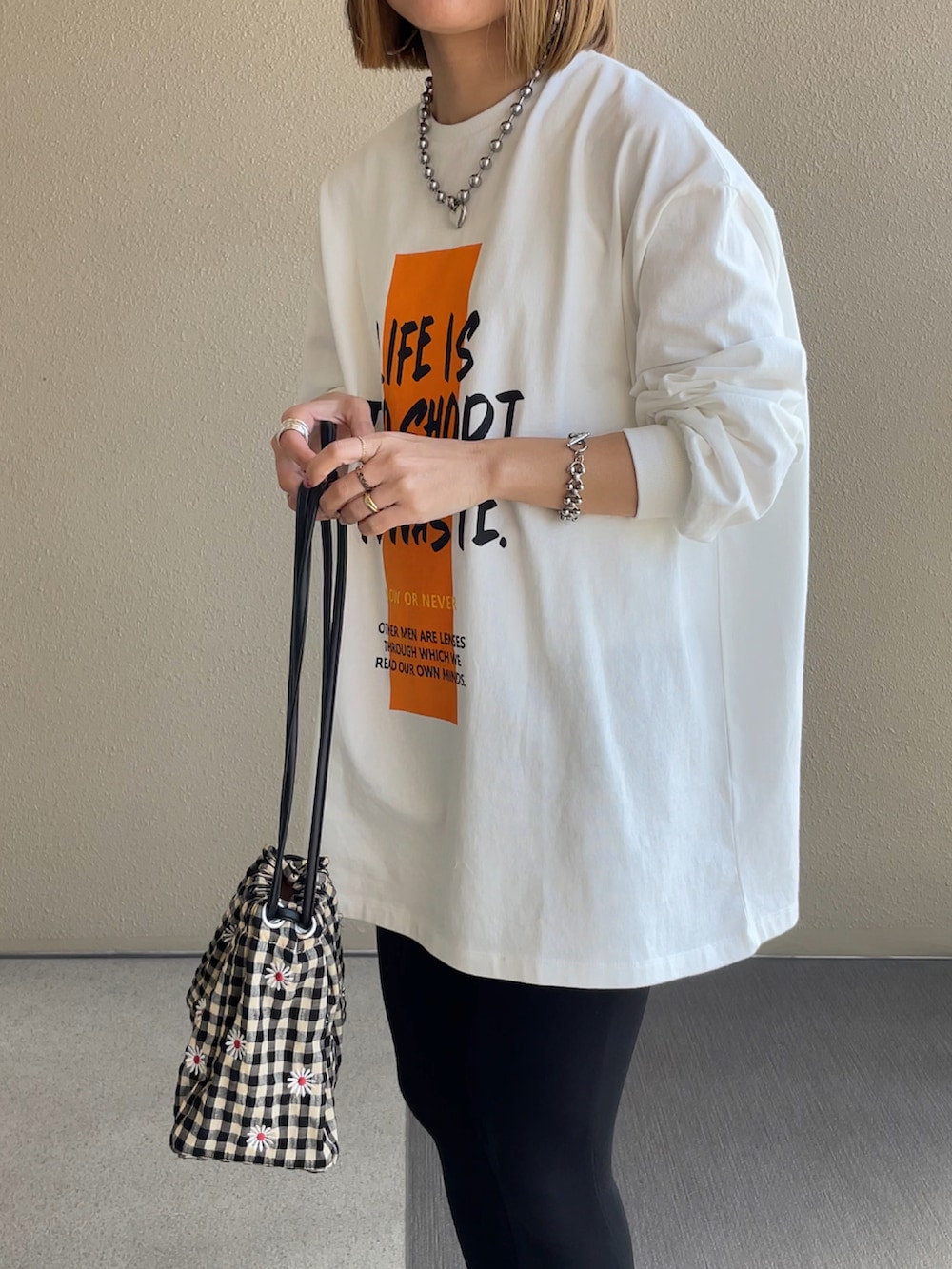 ホワイト系のTシャツ/カットソー、ブラック系のスニーカー、その他のハンドバッグを着用したレディースの春コーディネートの2枚目の写真