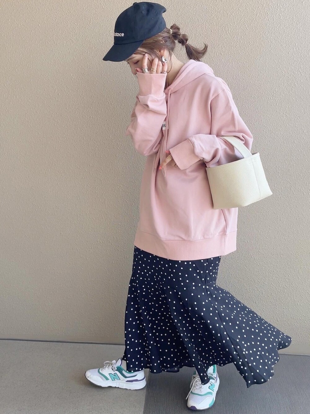 ピンク系のパーカー、ブラック系のスカート、ホワイト系のスニーカーを着用したレディースの冬コーディネートの2枚目の写真