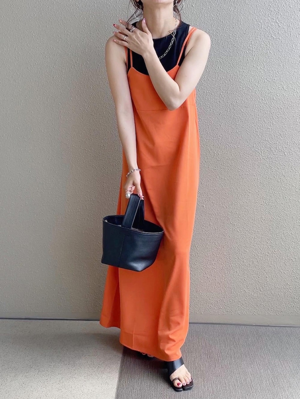 オレンジ系のワンピース、ブラック系のタンクトップ、ホワイト系のシャツ/ブラウスを着用したレディースの春コーディネートの2枚目の写真