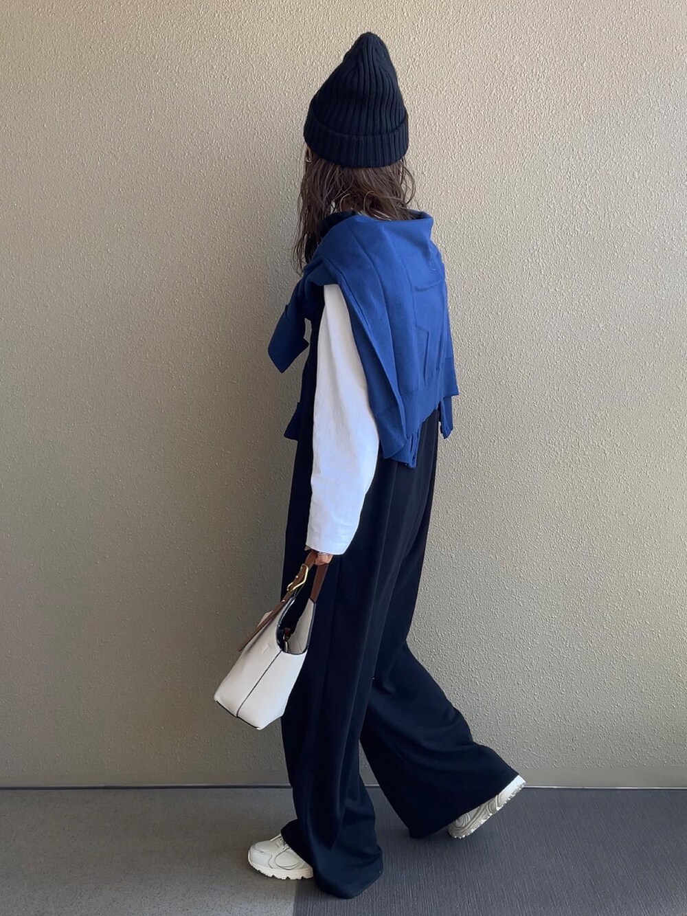 ブルー系のカーディガン/ボレロ、ブラック系のサロペット/オーバーオール、ホワイト系のスニーカーを着用したレディースの秋コーディネートの5枚目の写真