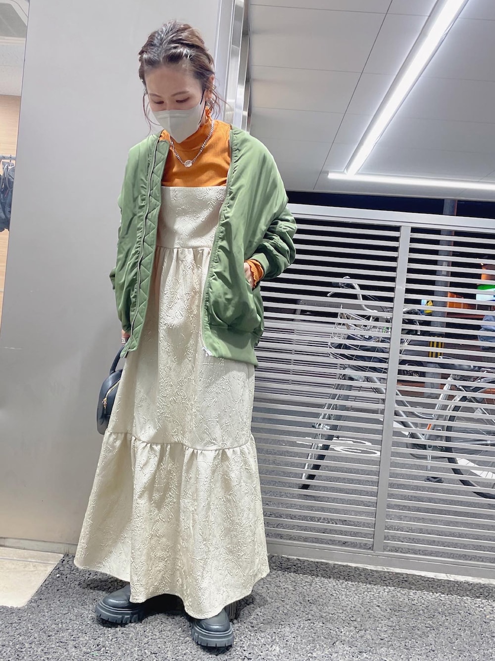 ブラック系のハンドバッグ、グリーン系のMA-1、オレンジ系のTシャツ/カットソーを着用したレディースの秋コーディネートの4枚目の写真