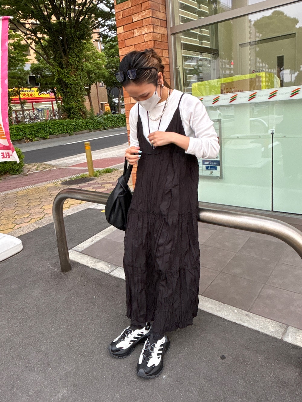 ホワイト系のTシャツ/カットソー、ブラック系のワンピース/ドレス、ホワイト系のサンダルを着用したレディースの春コーディネートの2枚目の写真