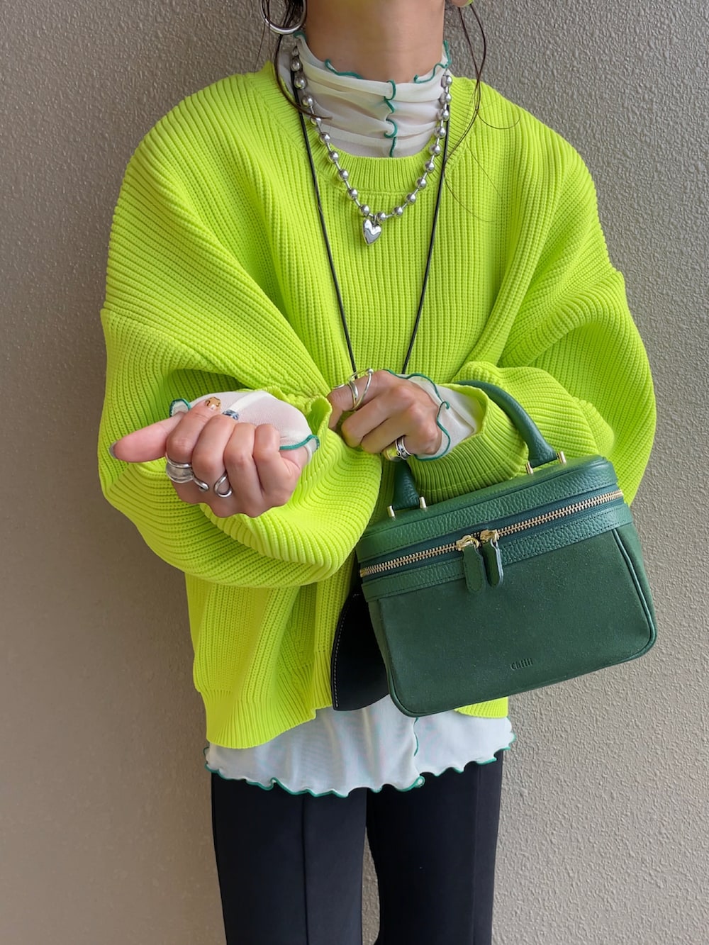 グリーン系のニット/セーター、ホワイト系のTシャツ/カットソー、ブラック系のスラックスを着用したレディースの秋コーディネートの2枚目の写真