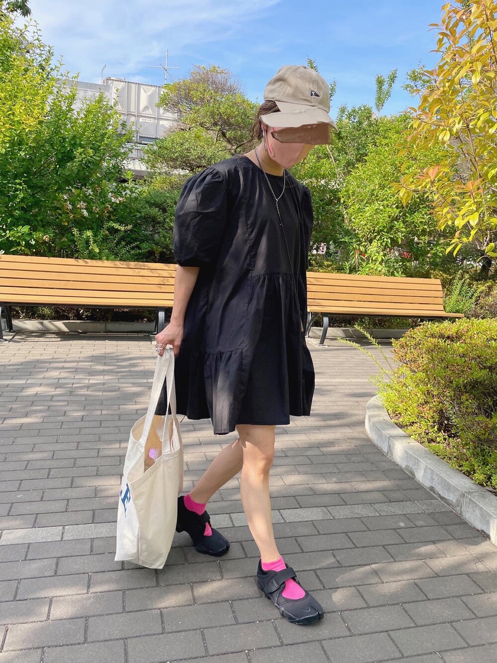 ブラック系のワンピース、ホワイト系のトートバッグ、ブラック系のサンダルを着用したレディースの夏コーディネートの4枚目の写真