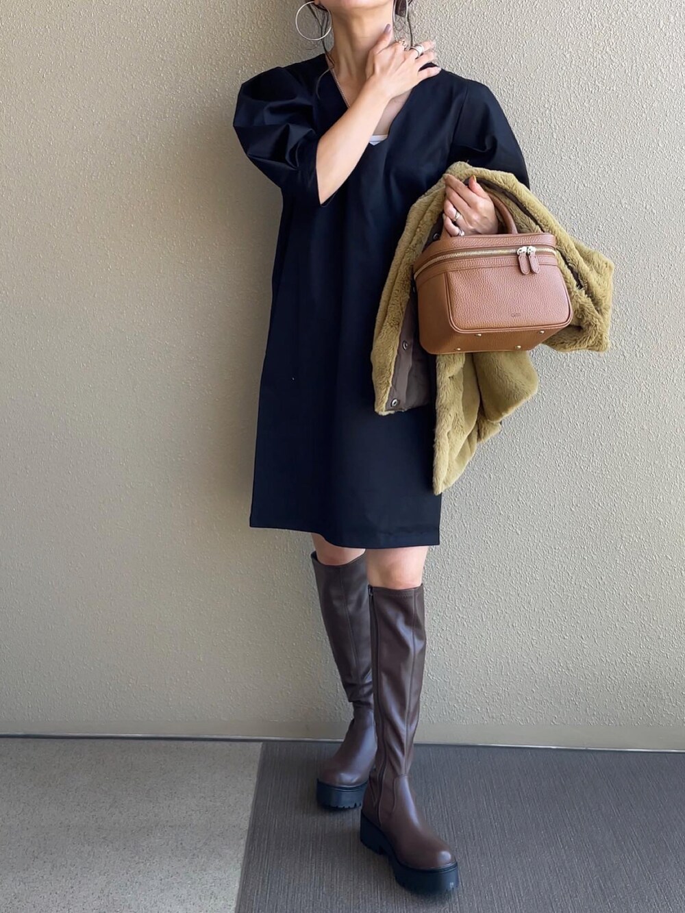 ブラック系のワンピース、イエロー系のベスト、ブラウン系のブーツを着用したレディースの秋コーディネートの3枚目の写真