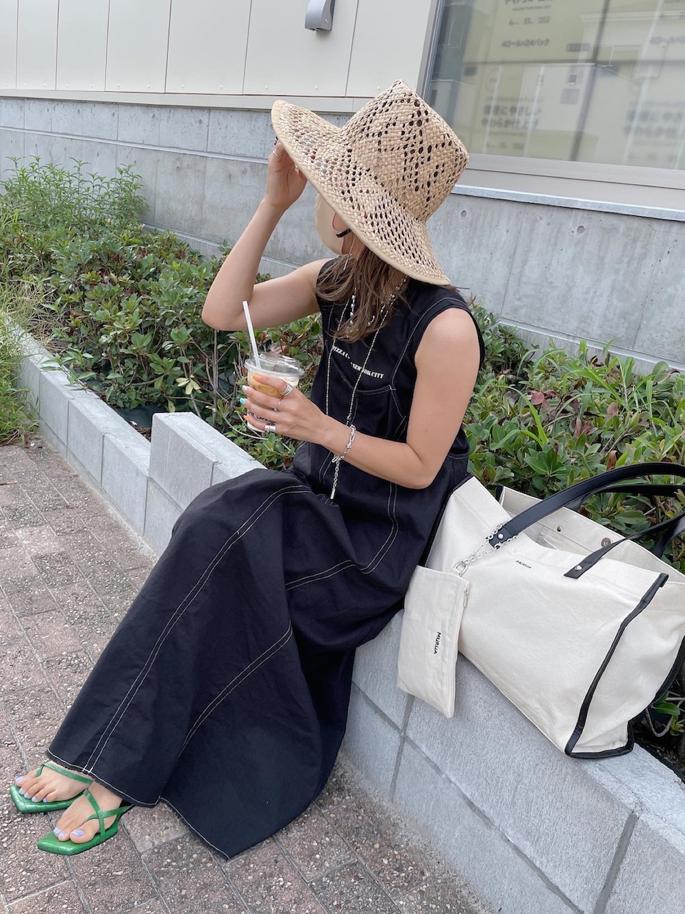 ブラック系のワンピース、ホワイト系のトートバッグ、グリーン系のサンダルを着用したレディースの夏コーディネートの3枚目の写真