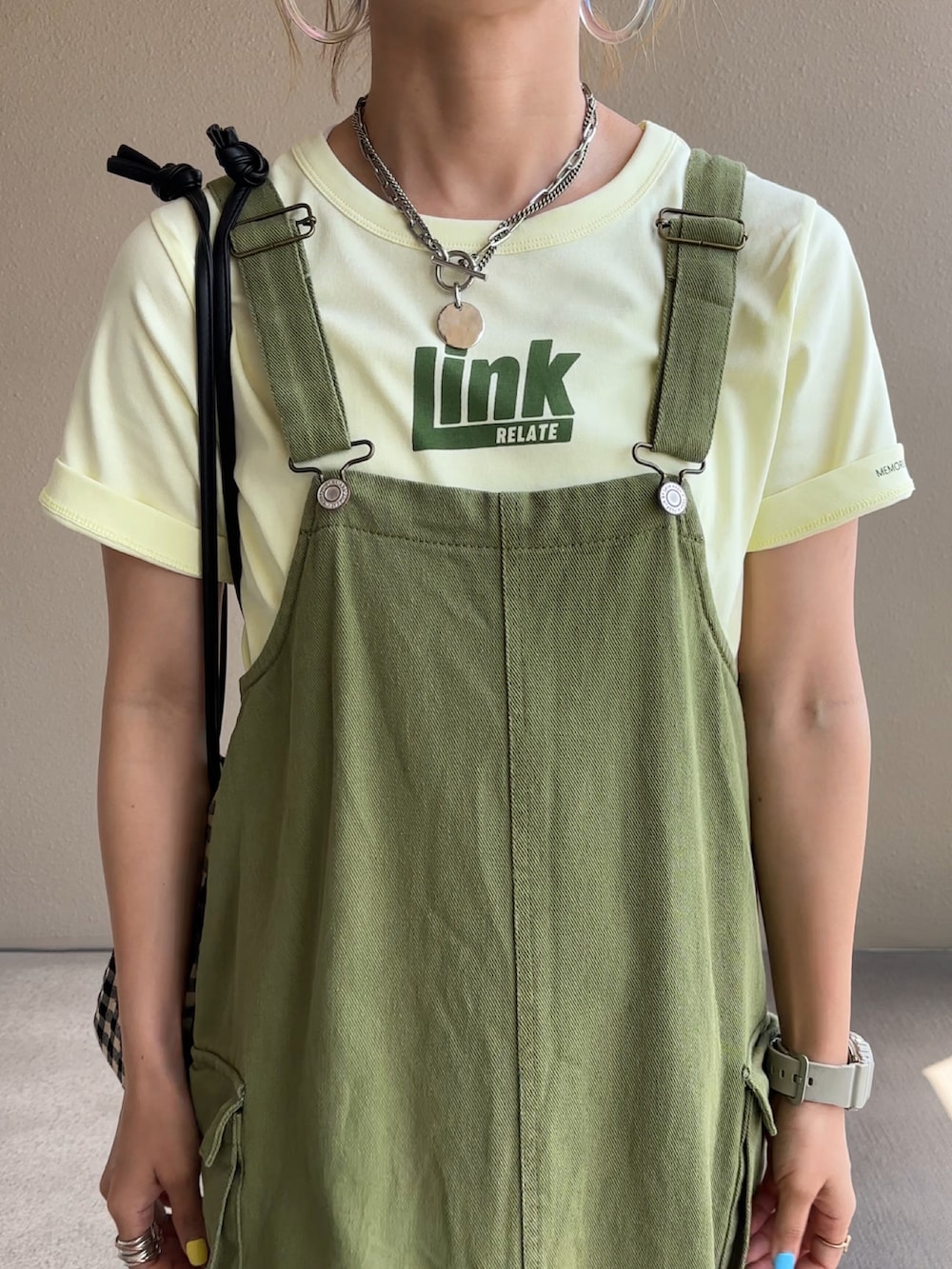 ベージュ系のTシャツ/カットソー、グリーン系のジャンパースカートを着用したレディースの夏コーディネートの3枚目の写真