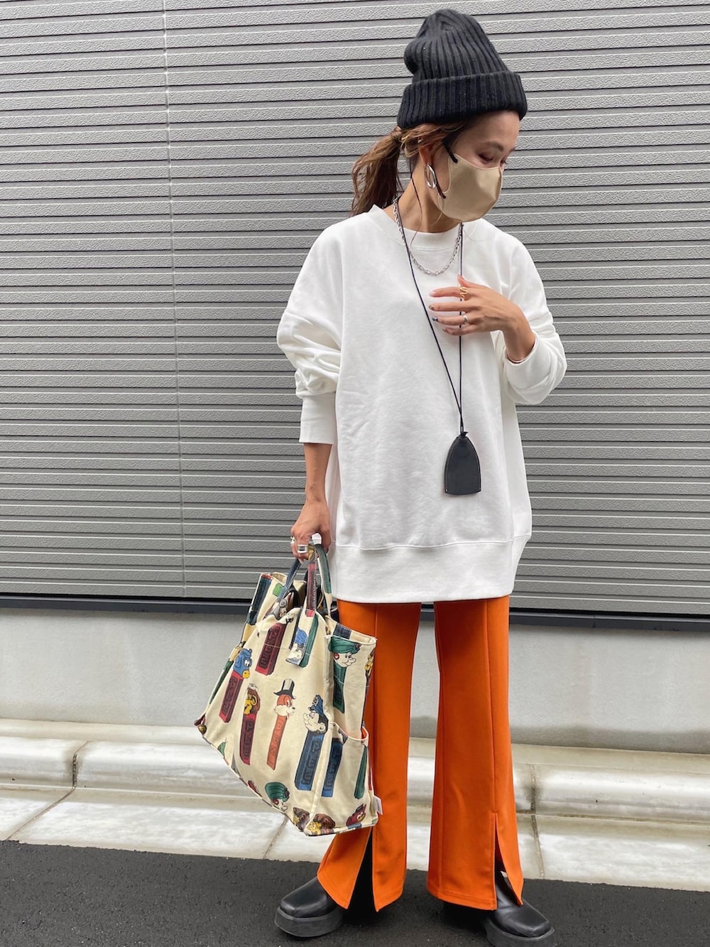 ホワイト系のスウェット、オレンジ系のスラックス、ブラック系のブーツを着用したレディースの秋コーディネートの2枚目の写真