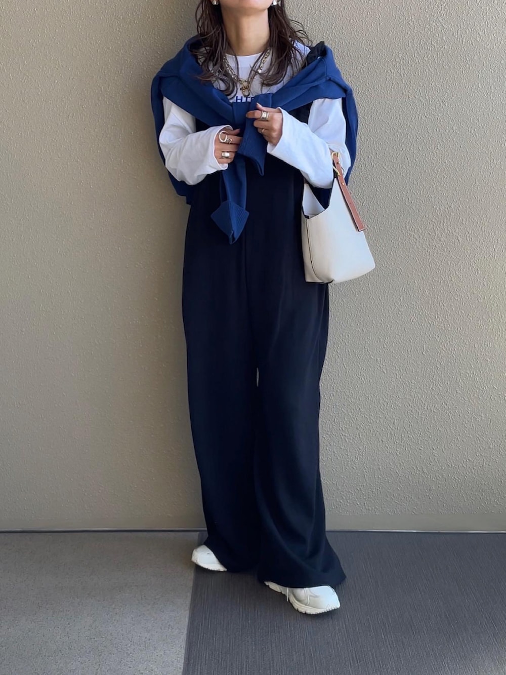 ブルー系のカーディガン/ボレロ、ブラック系のサロペット/オーバーオール、ホワイト系のスニーカーを着用したレディースの秋コーディネートの4枚目の写真