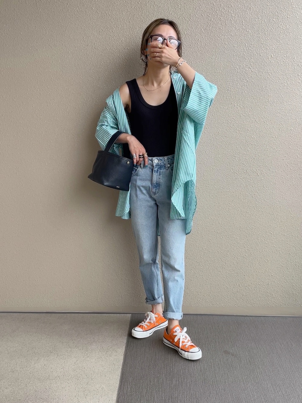 グリーン系のシャツ/ブラウス、オレンジ系のその他パンツ、ブルー系のデニムパンツを着用したレディースの春コーディネートの4枚目の写真