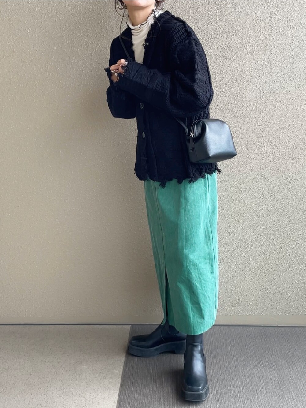 ブラック系のカーディガン/ボレロ、グレー系のショルダーバッグ、グリーン系のデニムスカートを着用したレディースの秋コーディネートの2枚目の写真