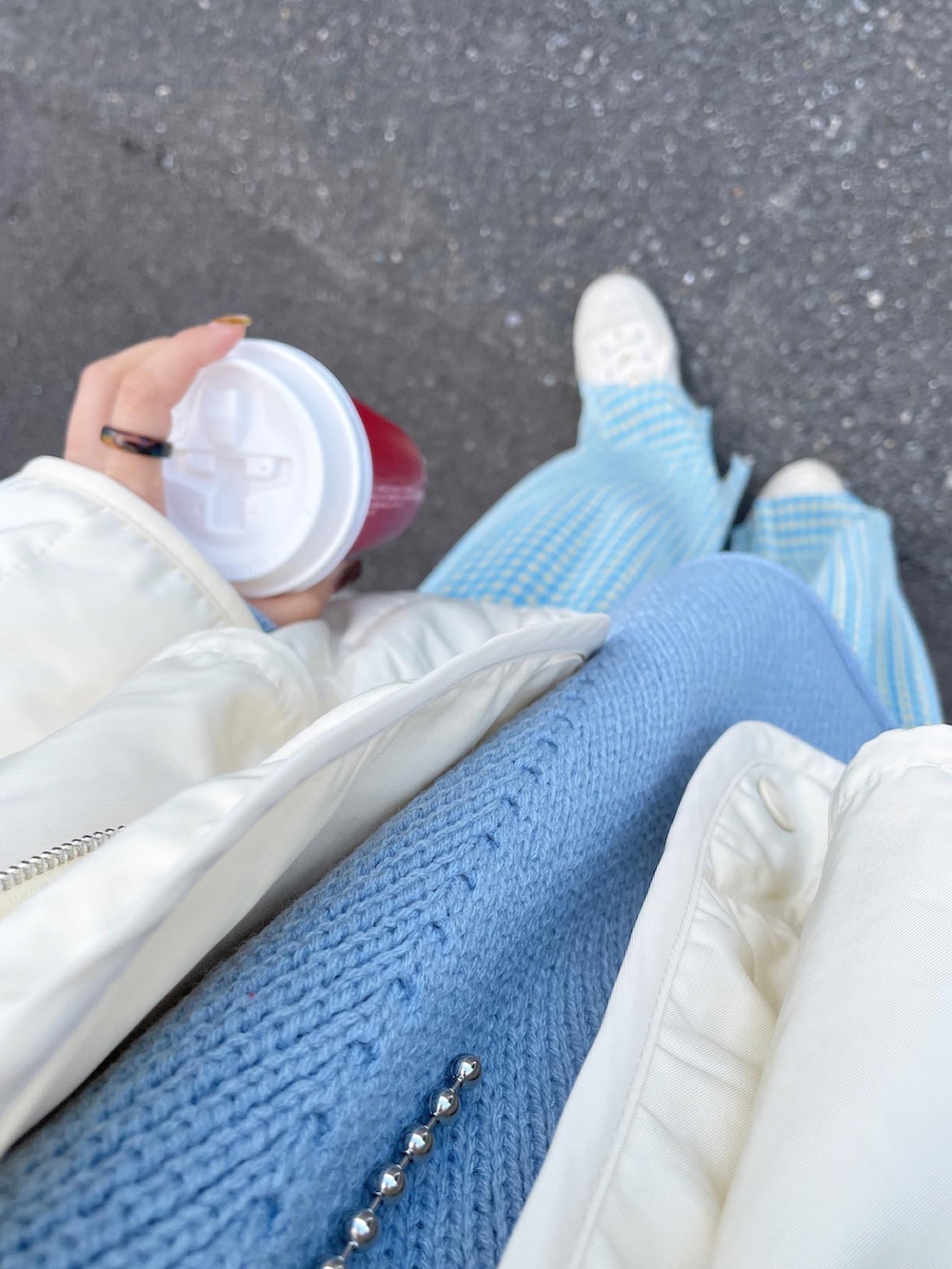 ホワイト系のダウンジャケット/コート、ブルー系のニット/セーター、ホワイト系のスニーカーを着用したレディースの冬コーディネートの4枚目の写真