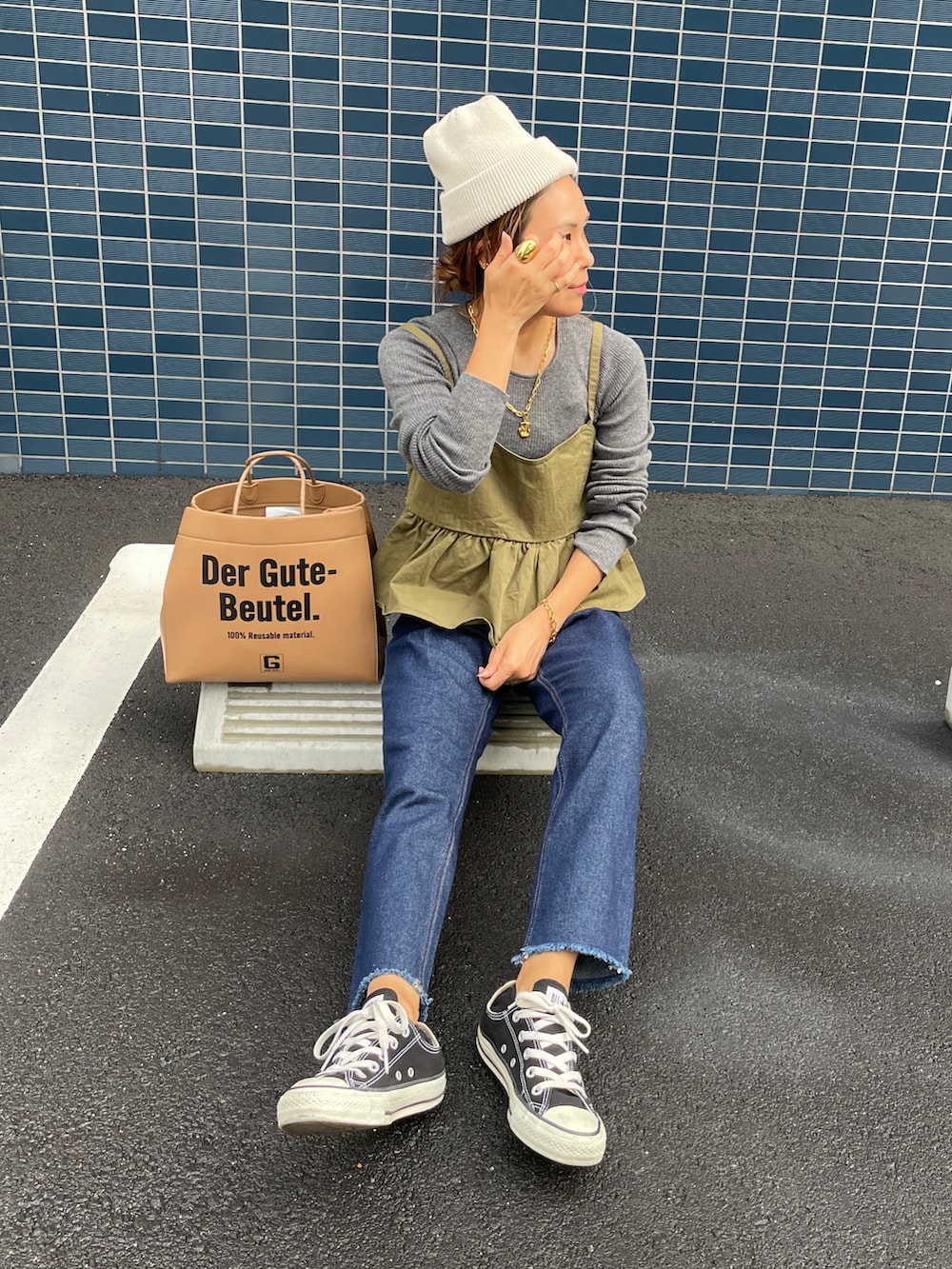 ブルー系のデニムパンツ、グレー系のニット/セーター、グリーン系のキャミソールを着用したレディースの秋コーディネートの2枚目の写真