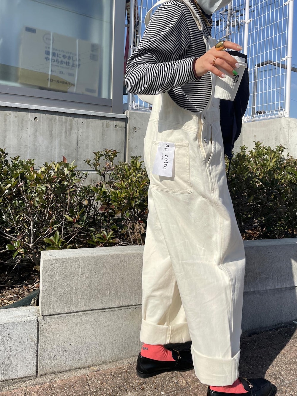 ブルー系のミリタリージャケット、ホワイト系のサロペット/オーバーオール、ホワイト系のハンドバッグを着用したレディースの春コーディネートの5枚目の写真