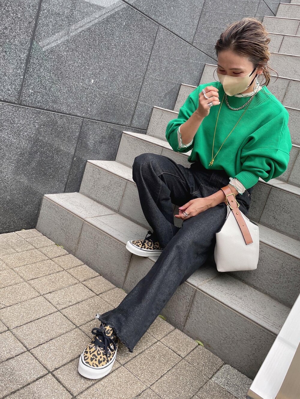 グリーン系のニット/セーター、ホワイト系のTシャツ/カットソー、ブラック系のデニムパンツを着用したレディースの秋コーディネートの5枚目の写真