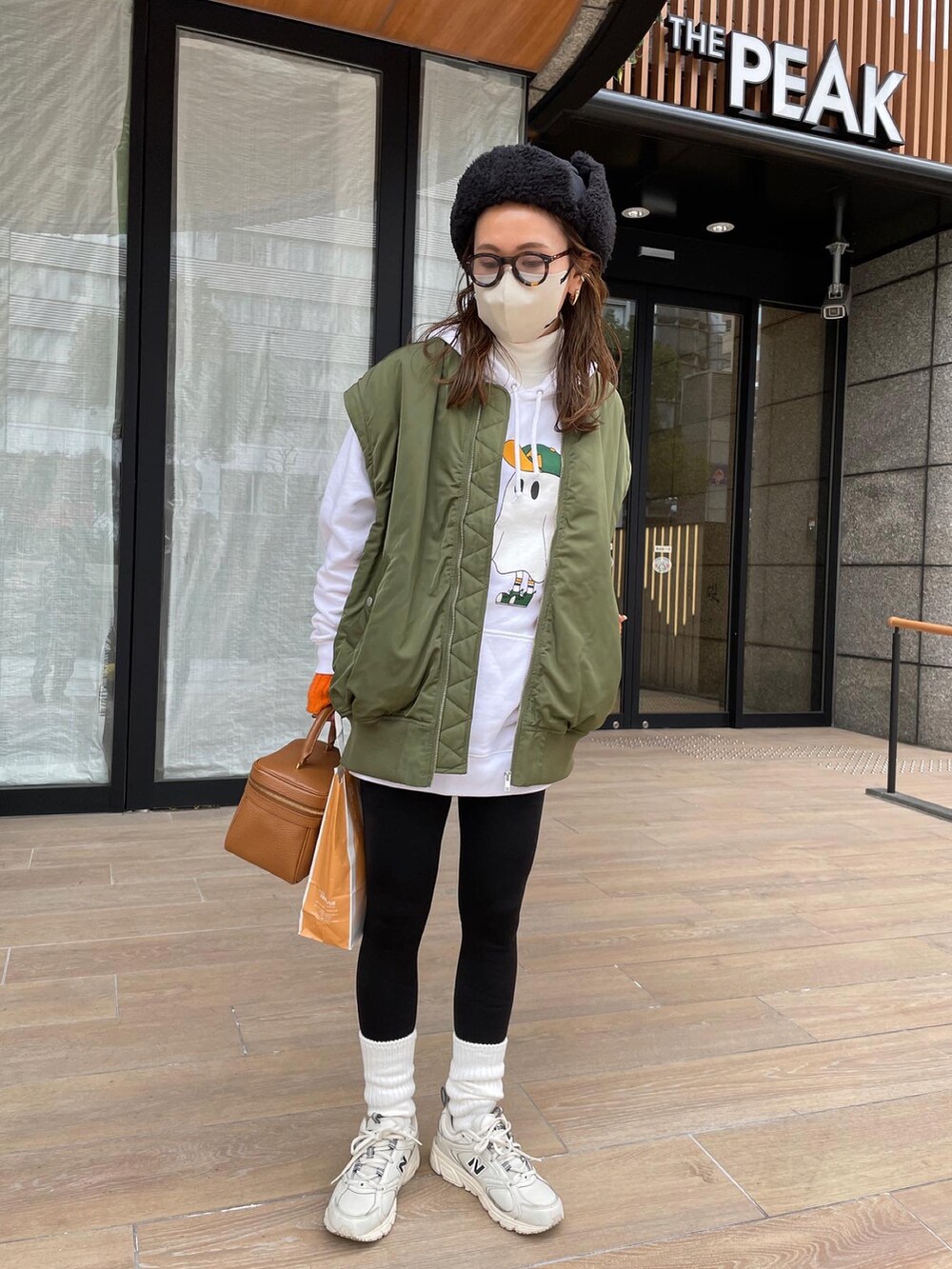 グリーン系のMA-1、ホワイト系のスニーカー、ブラック系のハットを着用したレディースの冬コーディネートの3枚目の写真