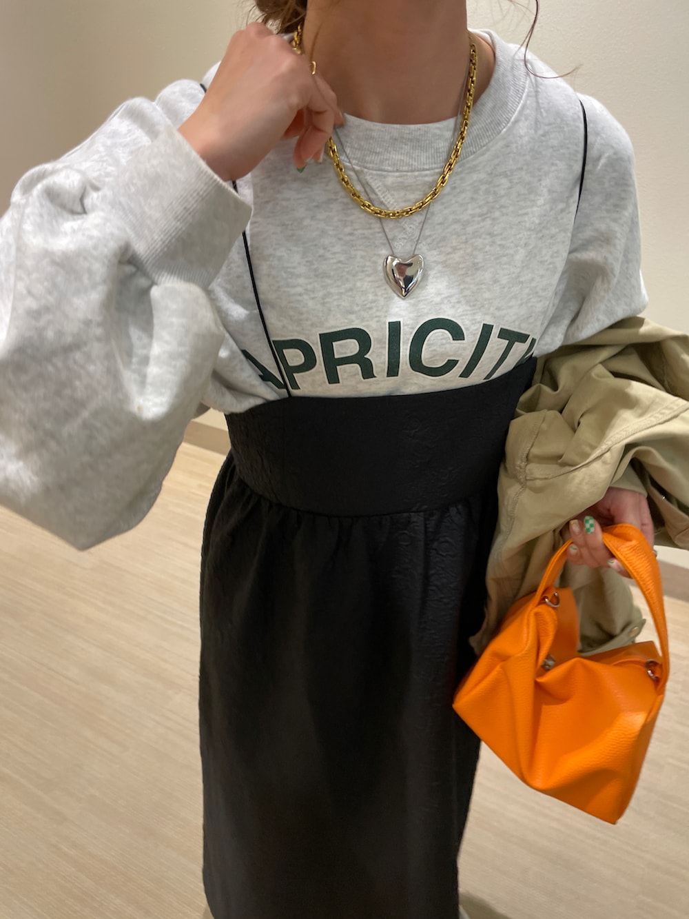 ベージュ系のミリタリージャケット、ベージュ系のスウェット、ブラック系のワンピースを着用したレディースの春コーディネートの5枚目の写真