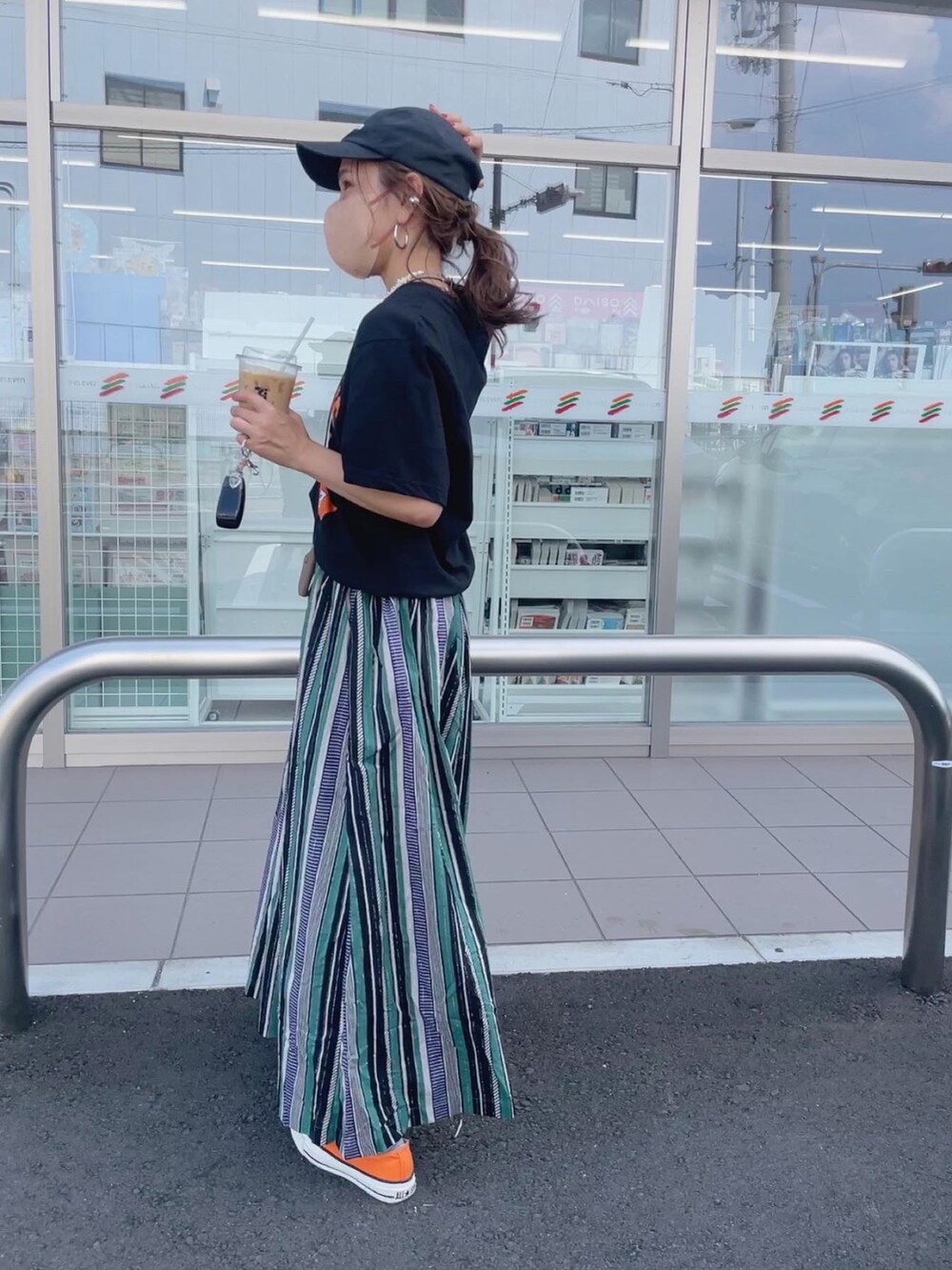 グリーン系のスカート、ホワイト系のトートバッグ、オレンジ系のスニーカーを着用したレディースの夏コーディネートの2枚目の写真