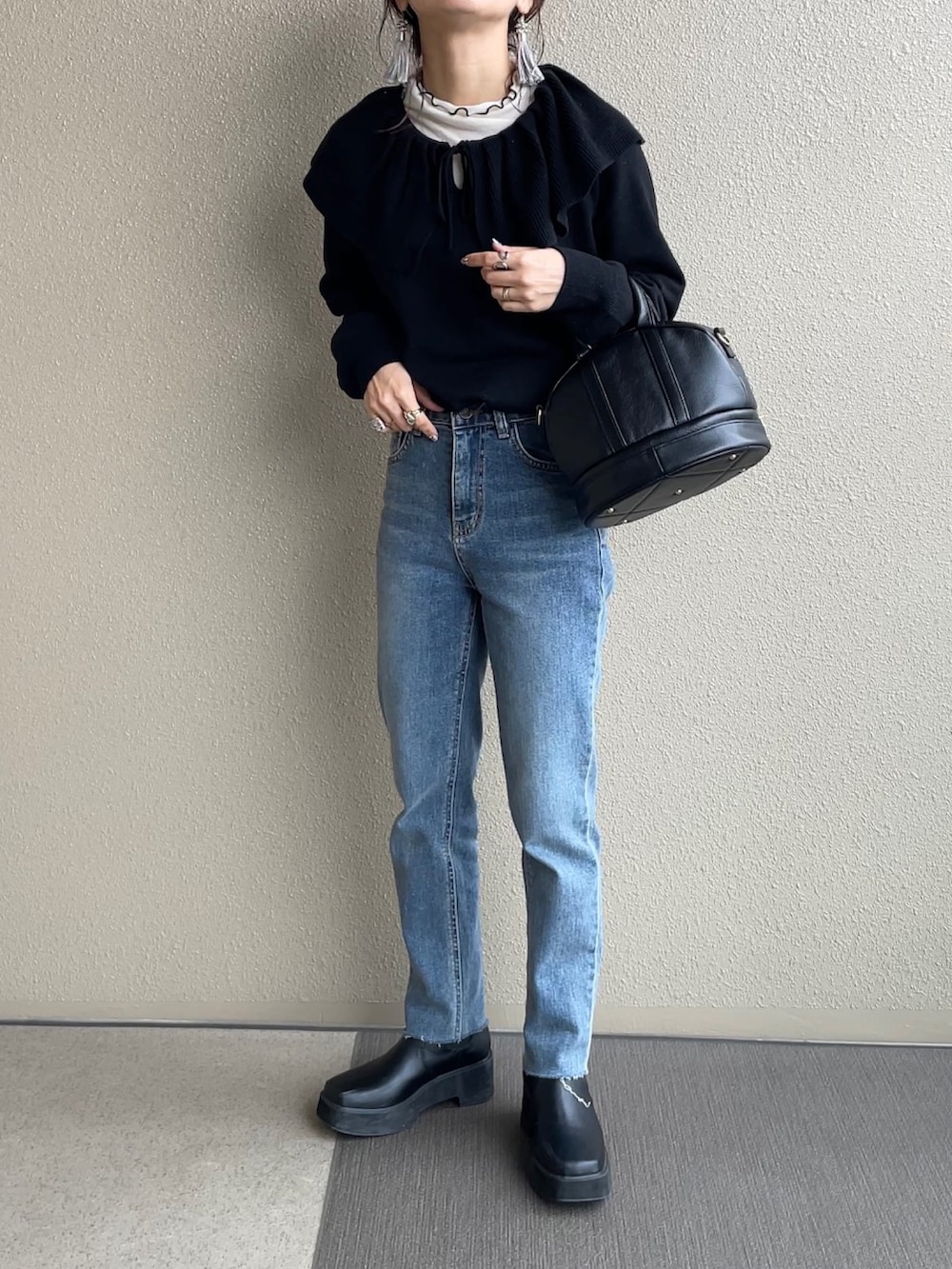 ベージュ系のノーカラーコート、ブラック系のニット/セーター、ブラック系のショルダーバッグを着用したレディースの冬コーディネートの2枚目の写真