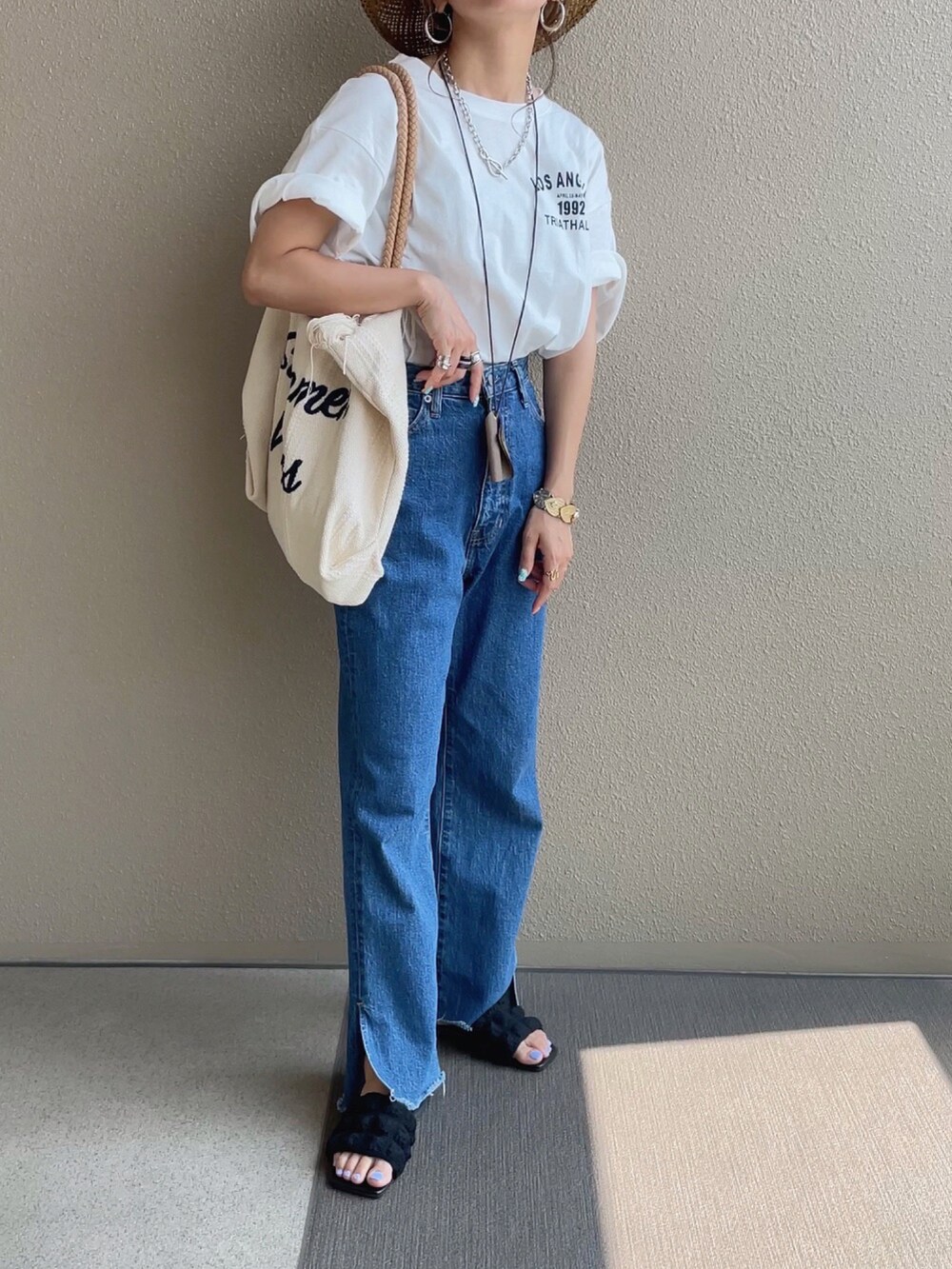 ホワイト系のTシャツ/カットソー、ホワイト系のトートバッグ、ブルー系のデニムパンツを着用したレディースの夏コーディネートの2枚目の写真