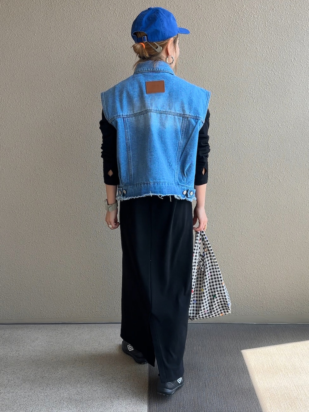 ブルー系のベスト、ブラック系のワンピースを着用したレディースの春コーディネートの4枚目の写真