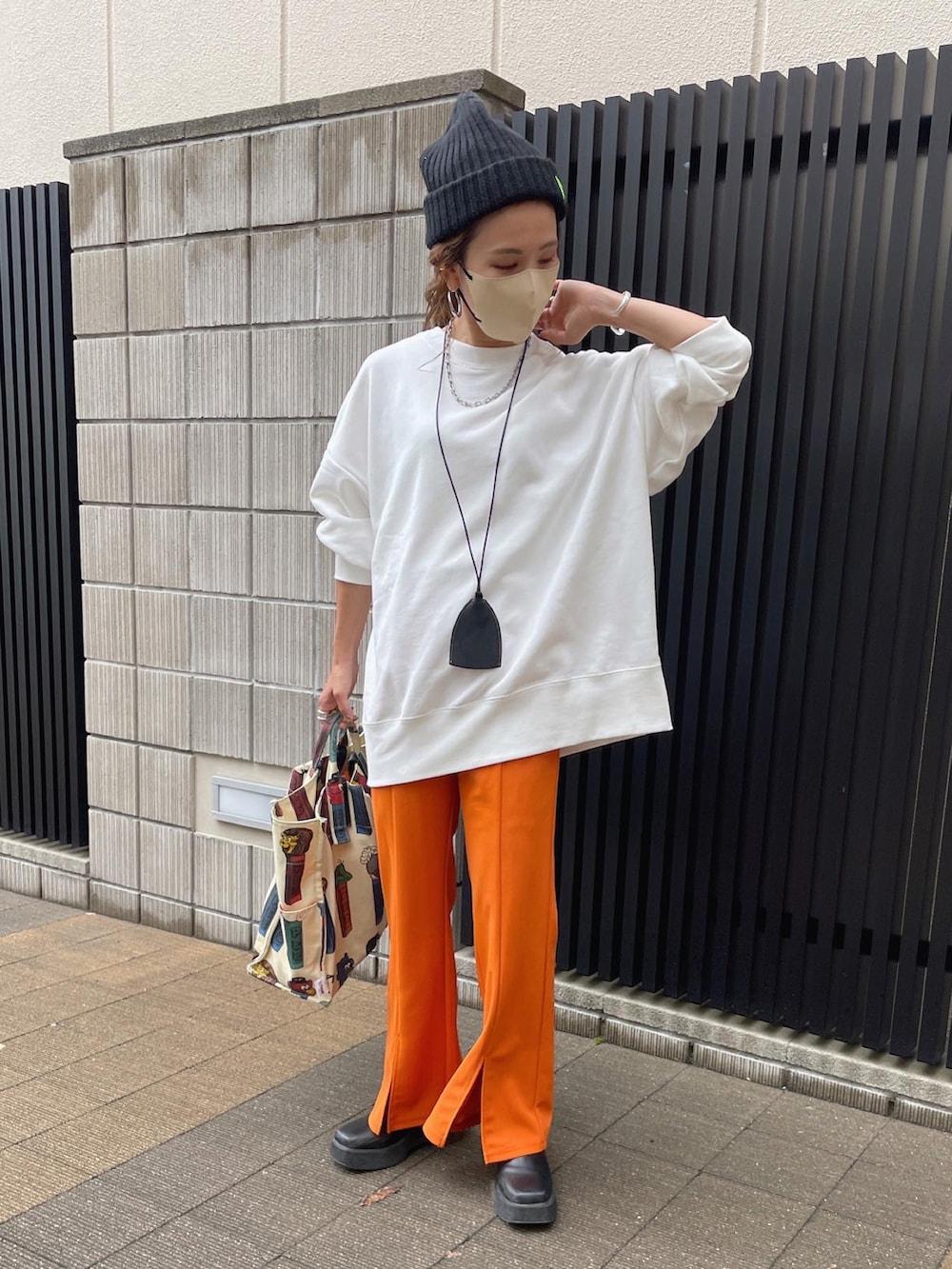 ホワイト系のスウェット、オレンジ系のスラックス、ブラック系のブーツを着用したレディースの秋コーディネートの4枚目の写真