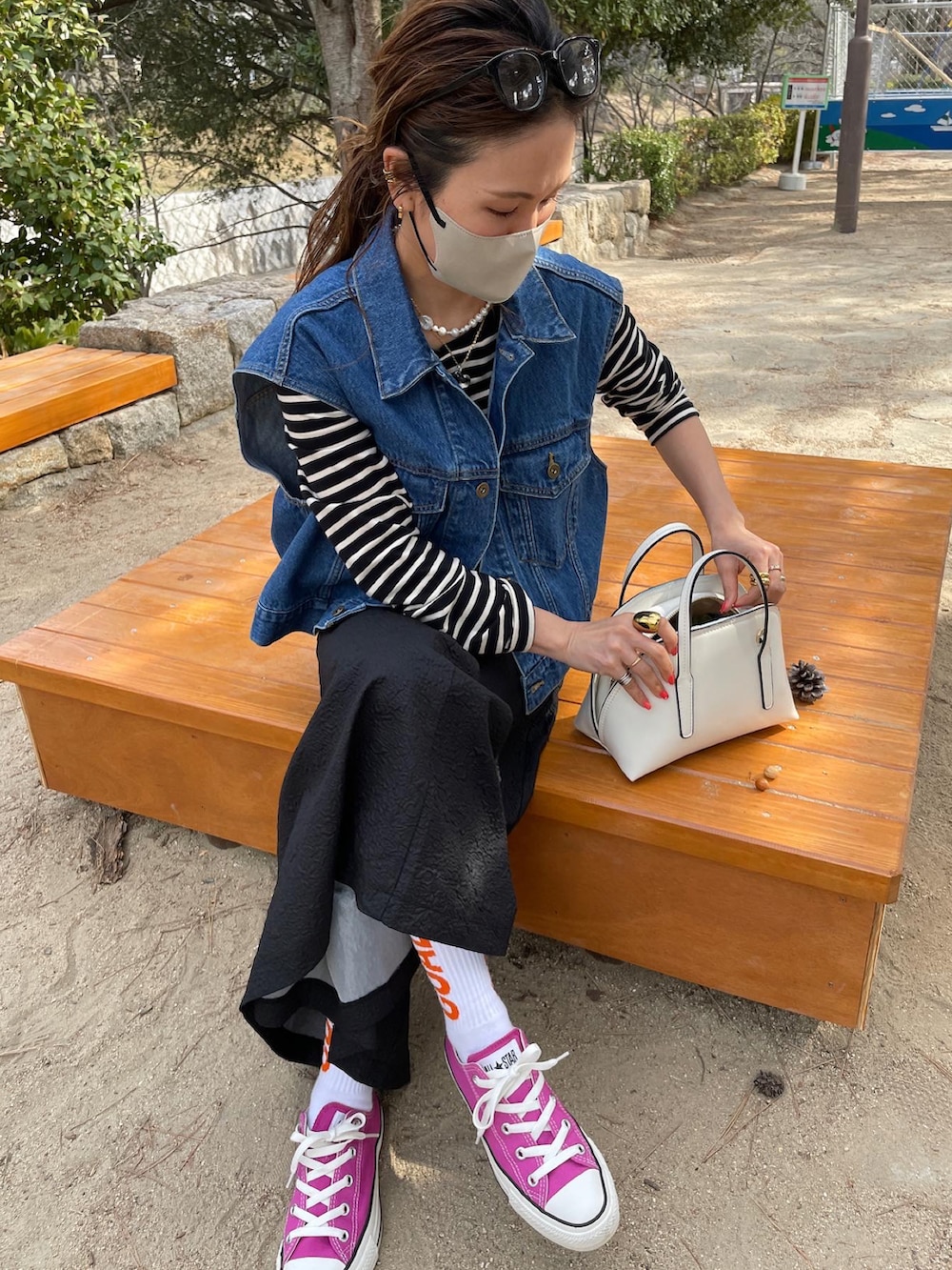 ブルー系のベスト、ブラック系のワンピース、ピンク系のスニーカーを着用したレディースの春コーディネートの4枚目の写真