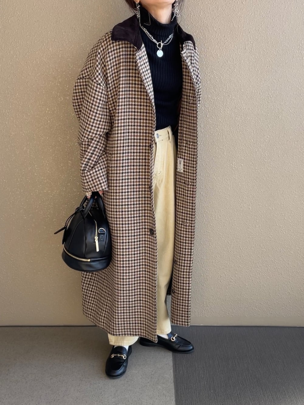 ブラック系のショルダーバッグ、ベージュ系のパンツ、ブラウン系のステンカラーコートを着用したレディースの冬コーディネートの2枚目の写真