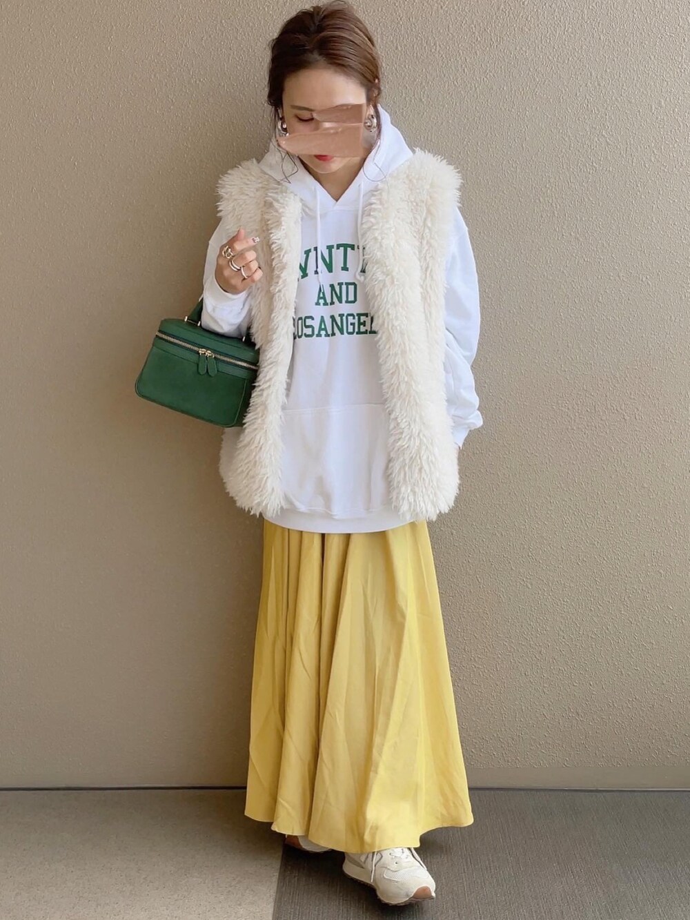 ホワイト系のパーカー、ホワイト系のベスト、ベージュ系のスニーカーを着用したレディースの冬コーディネートの2枚目の写真