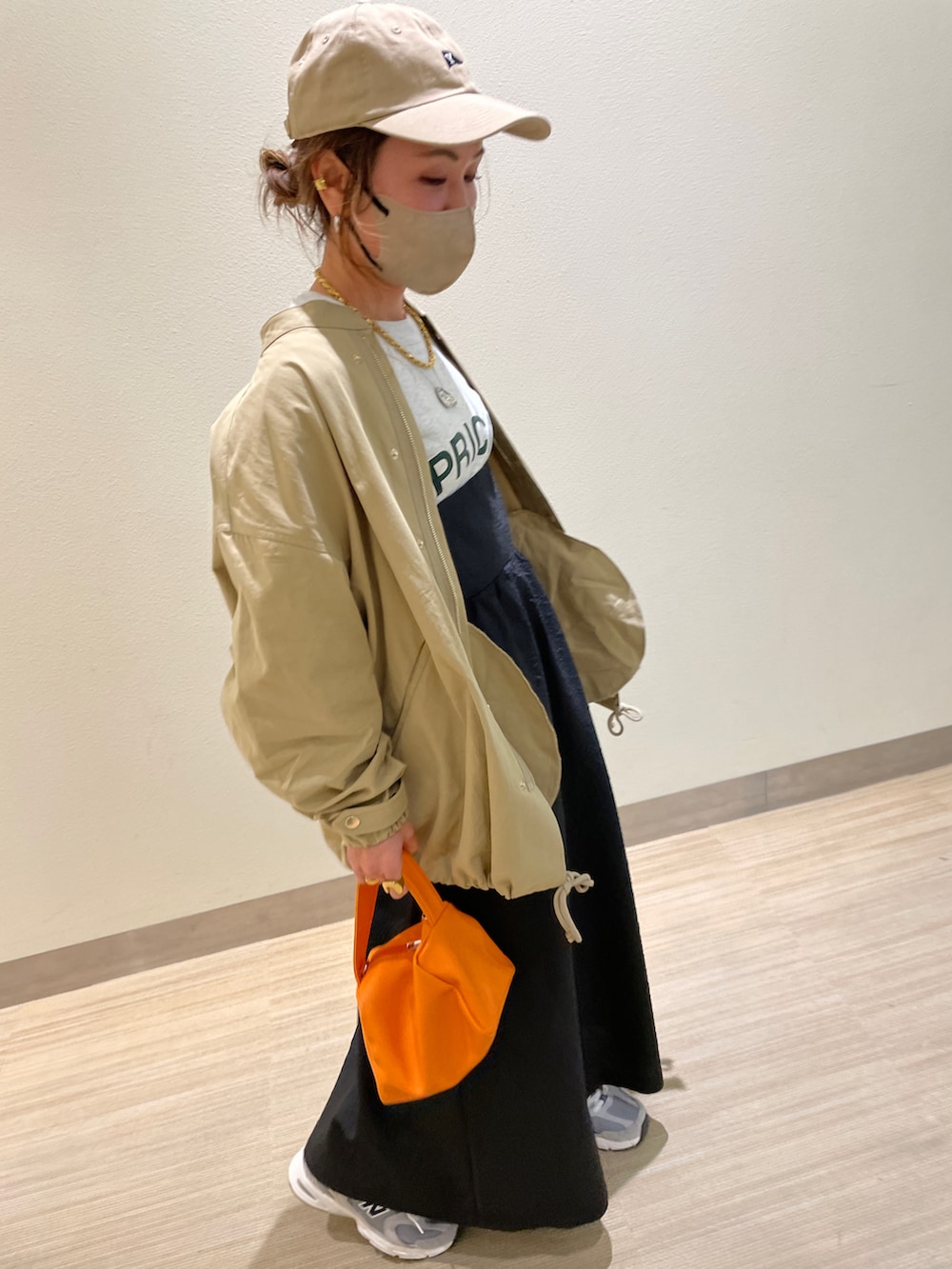 ベージュ系のミリタリージャケット、ベージュ系のスウェット、ブラック系のワンピースを着用したレディースの春コーディネートの2枚目の写真