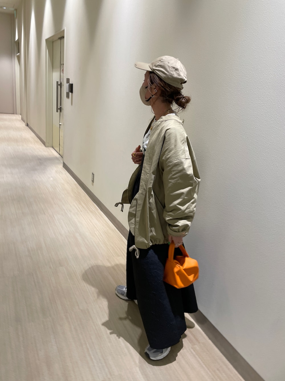 ベージュ系のミリタリージャケット、ベージュ系のスウェット、ブラック系のワンピースを着用したレディースの春コーディネートの3枚目の写真