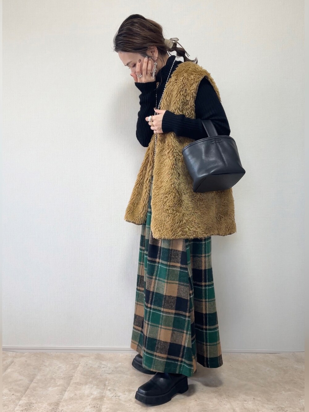 グリーン系のスカート、ブラウン系のベスト、ブラック系のその他アウターを着用したレディースの冬コーディネートの4枚目の写真