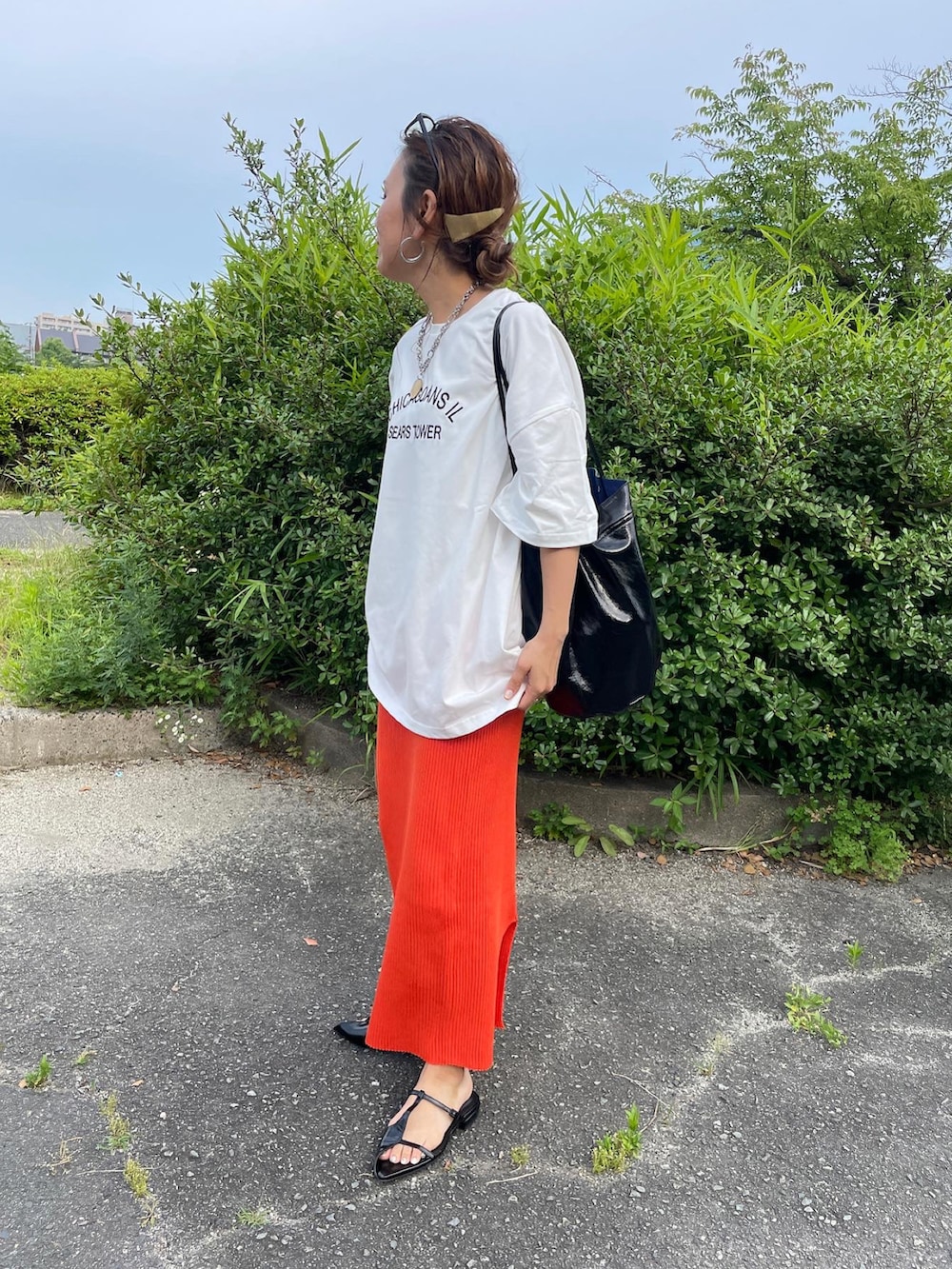 ホワイト系のTシャツ/カットソー、オレンジ系のスカート、ブラック系のショルダーバッグを着用したレディースの夏コーディネートの4枚目の写真