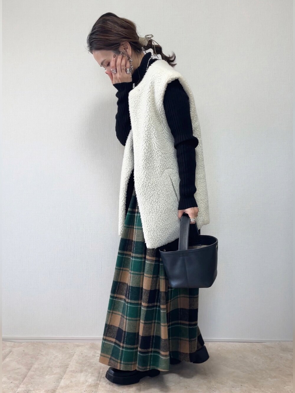 グリーン系のスカート、ブラウン系のベスト、ブラック系のその他アウターを着用したレディースの冬コーディネートの5枚目の写真