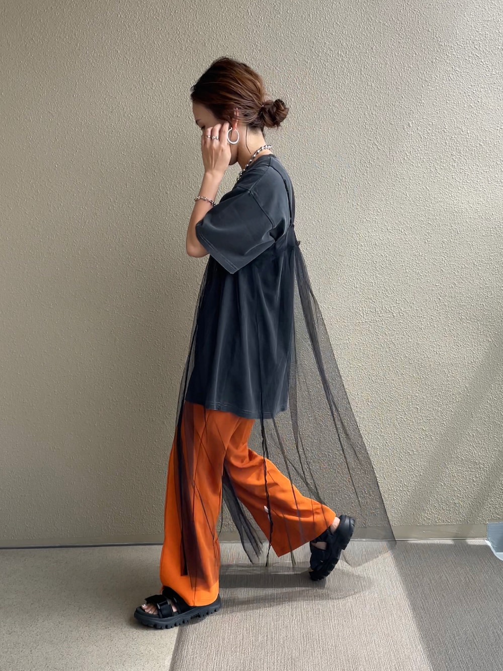 ブラック系のTシャツ/カットソー、オレンジ系のスラックス、ブラック系のワンピースを着用したレディースの夏コーディネートの3枚目の写真