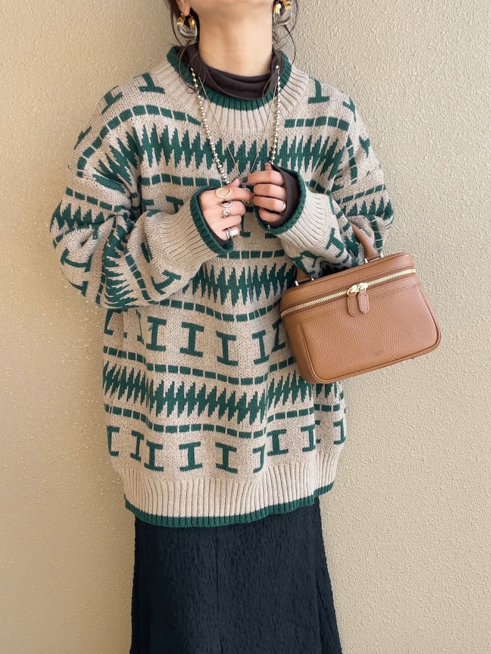 グリーン系のニット/セーター、ブラック系のスカート、ブラック系のパンプスを着用したレディースの冬コーディネートの2枚目の写真