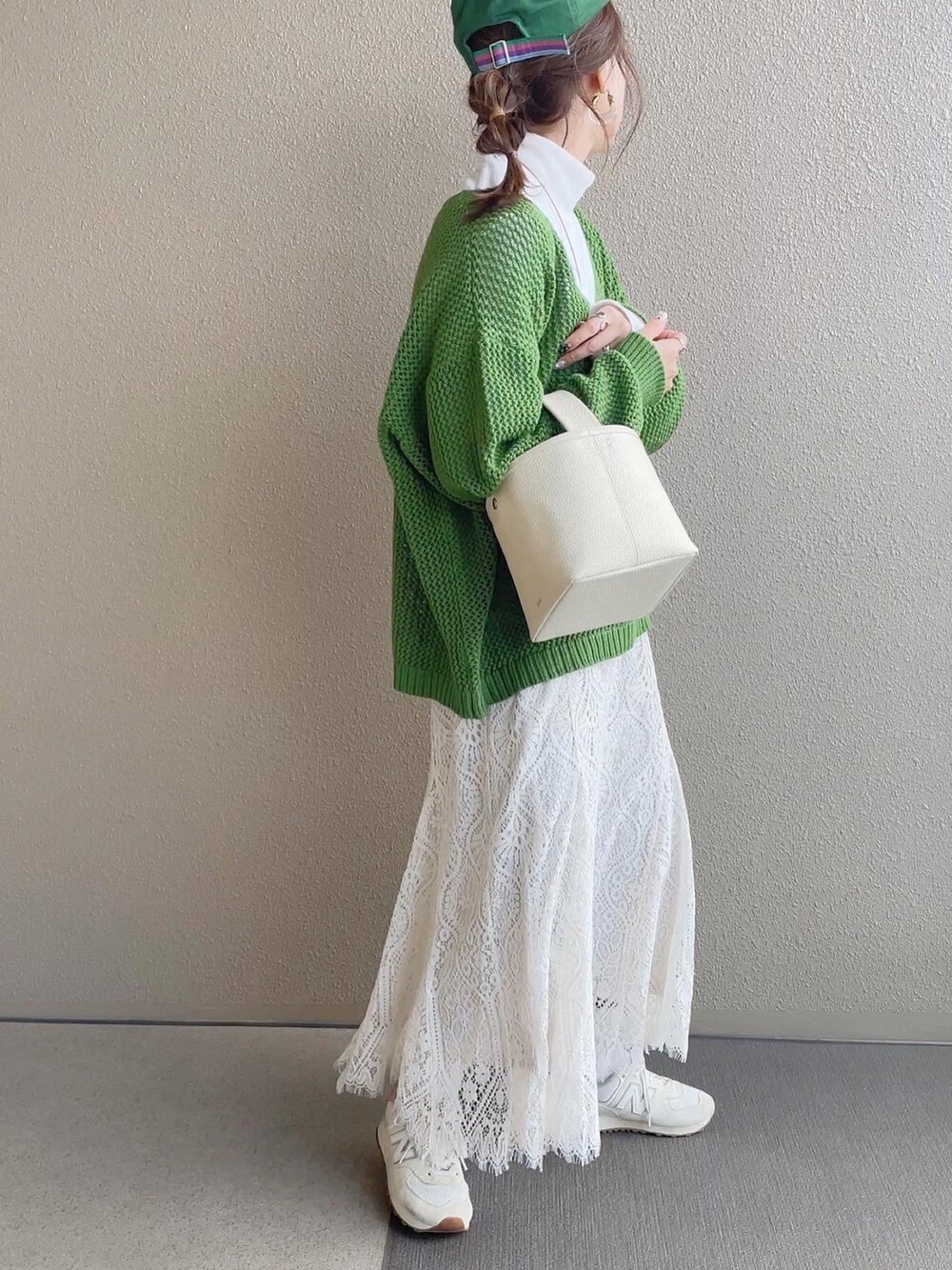 グリーン系のニット/セーター、ホワイト系のスカート、ベージュ系のスニーカーを着用したレディースの冬コーディネートの2枚目の写真