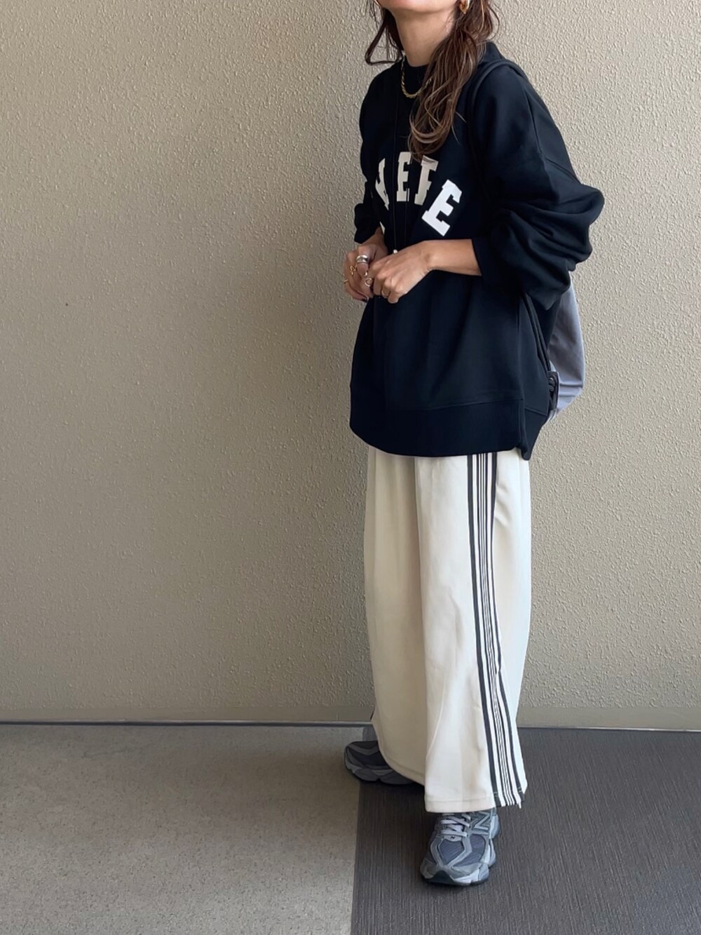 ブラック系のスウェット、ベージュ系のスカート、ブラック系のその他パンツを着用したレディースの秋コーディネートの2枚目の写真