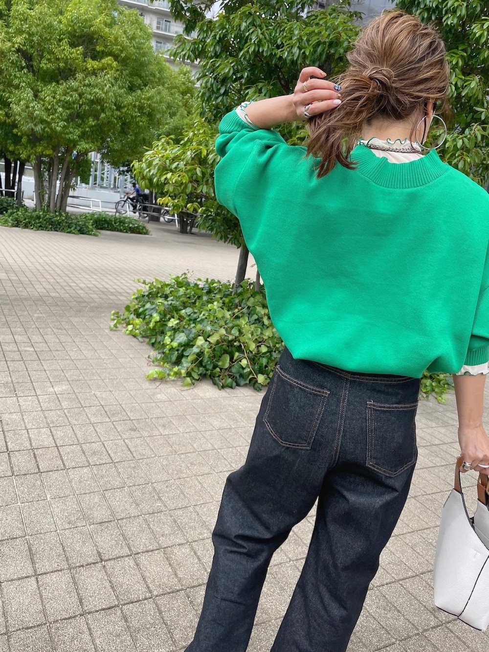 グリーン系のニット/セーター、ホワイト系のTシャツ/カットソー、ブラック系のデニムパンツを着用したレディースの秋コーディネートの4枚目の写真