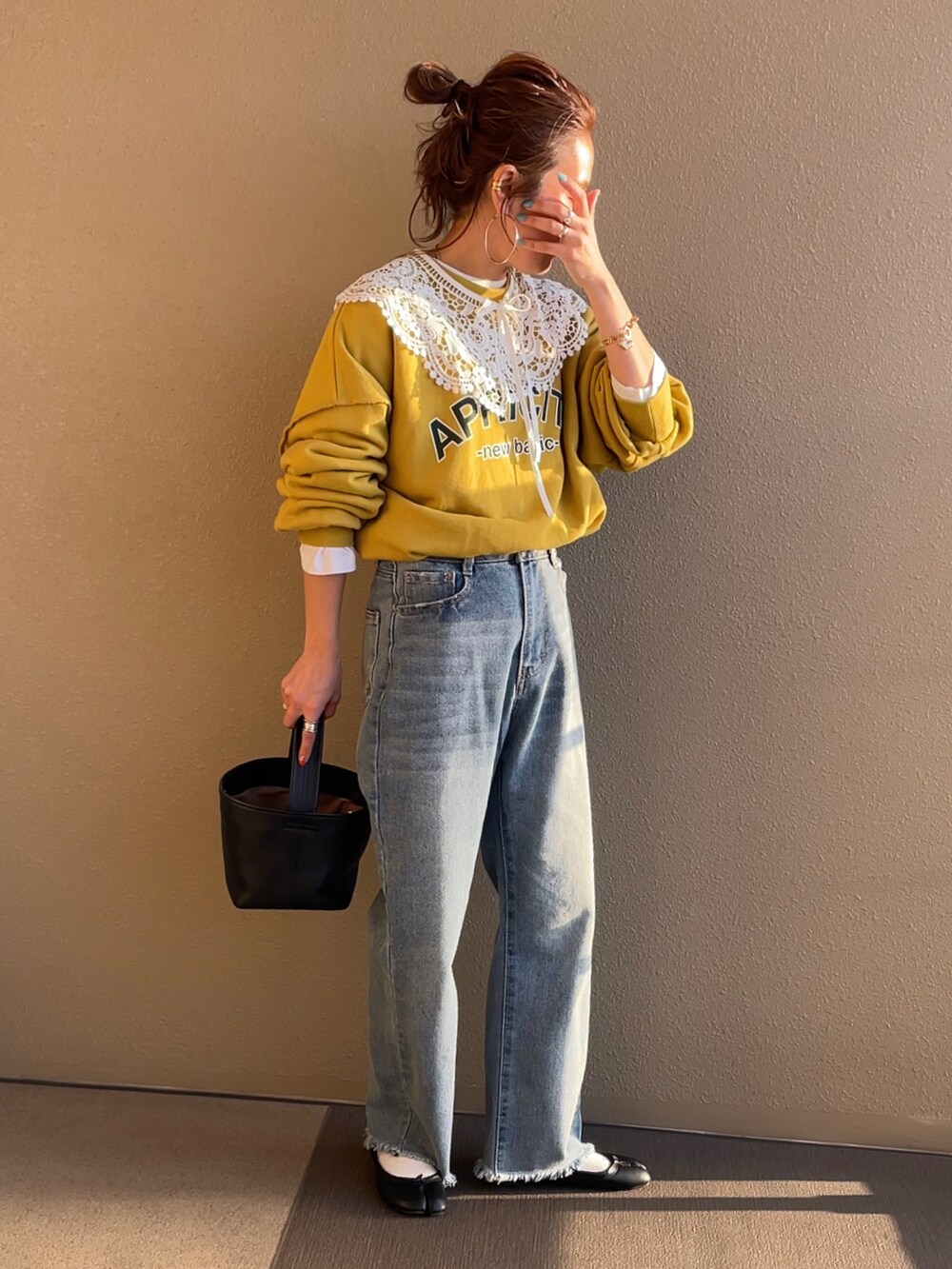 イエロー系のスウェット、ブルー系のデニムパンツを着用したレディースの冬コーディネートの2枚目の写真