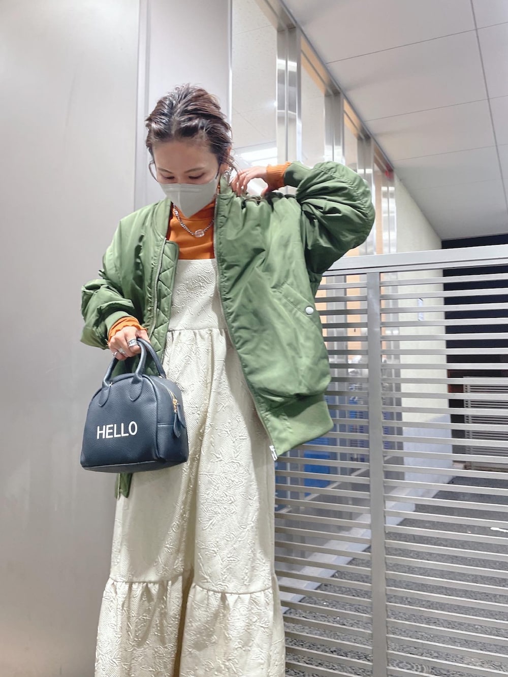 ブラック系のハンドバッグ、グリーン系のMA-1、オレンジ系のTシャツ/カットソーを着用したレディースの秋コーディネートの2枚目の写真